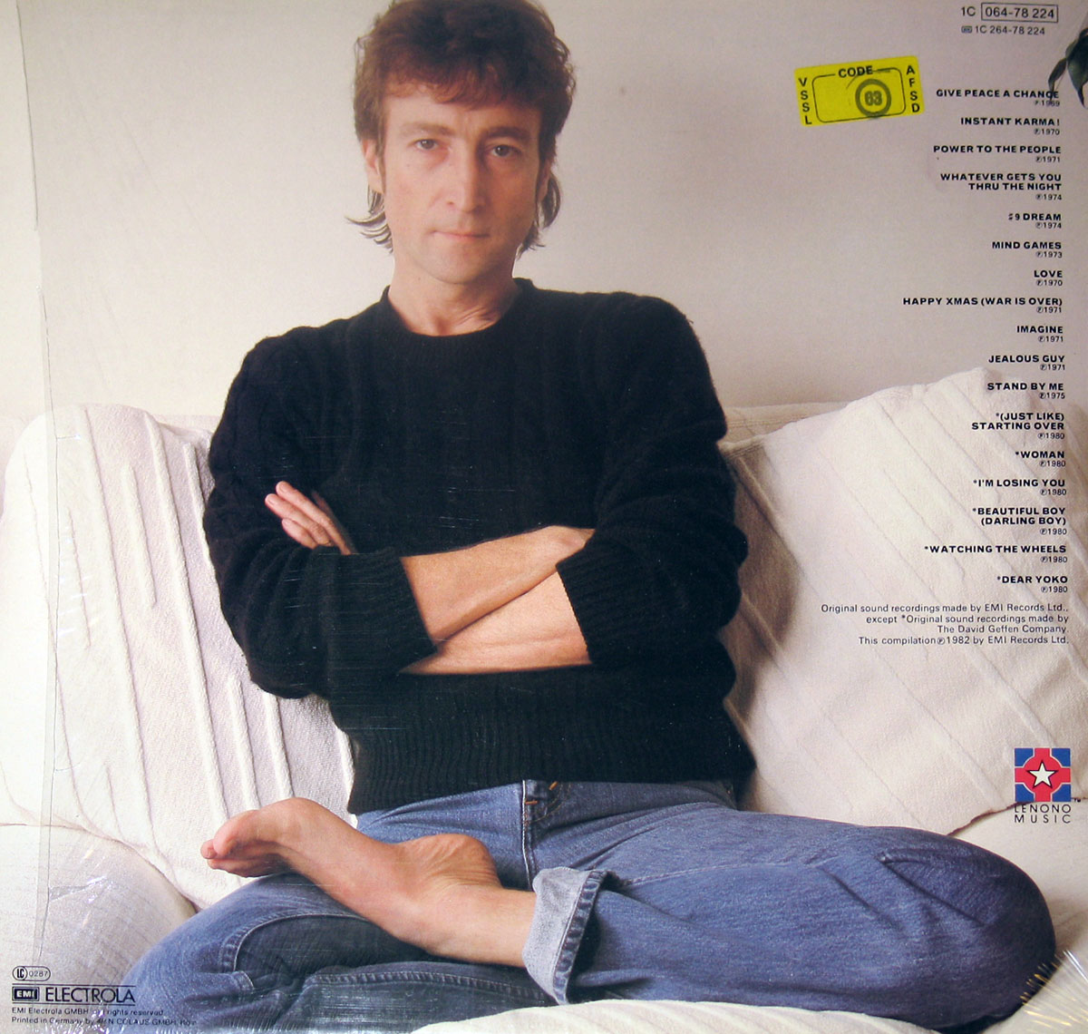 Photo of John Lennon sitting on a couch with legs crossed